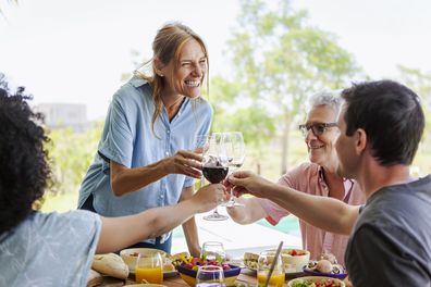 Happy family toasting wine glasses sitting at lunch table
