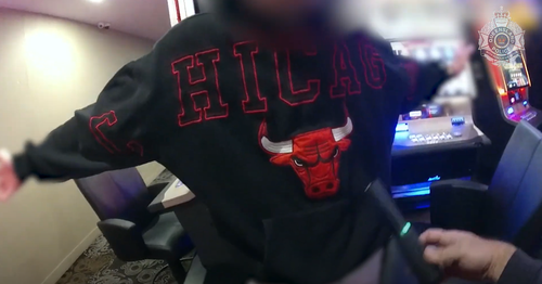A man being wanded by police in a pokies room.