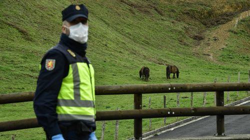 Spanish police officer blocks the road for vehicles to the border between Spain and France near the Pyrenees Spanish village of Dantxarinea.