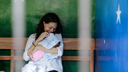 Heather Mack smiles as she holds her baby in a cell before her sentence demand trial in Denpasar, Bali. (Getty Images)