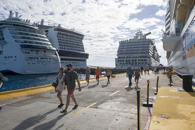 Mahahual, Mexico - January 6, 2022: Passengers,some wearing face masks, disembark from one of several cruise ships, including the Liberty of the Seas, Carnival Pride,  MSC Meraviglia, and the Serenade of the Seas, docked on Mexico's Costa Maya.