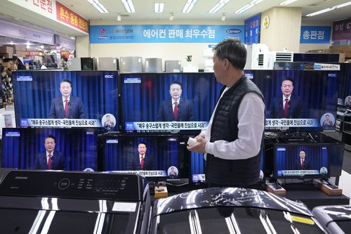 A man watches television screens showing South Korean President Yoon Suk-yeol's broadcast