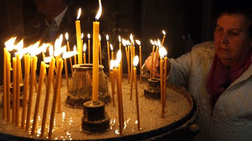 An Orthodox Bosnian Serb woman lights candles during the Easter service in Sarajevo Cathedral, in Sarajevo, Bosnia and Herzegovina. (AP).