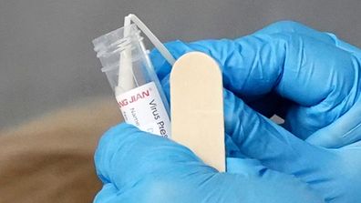 A medical worker places a sample from a person in a tube at a drive-through COVID-19 pop-up testing clinic at the Keilor Community Hub in Melbourne.