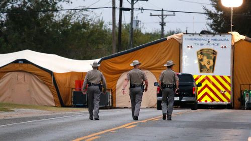 Three Texas State Troopers walk up the street to the command tents. (AAP)