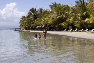 Bocas del Drago, Colón Island, Panamá - February 23, 2015: People on the beach and in the sea enjoying your holidays. Some motor boats on the shore of the Caribbean Sea. A woman and two girls walking on water. Umbrellas and lounge chairs for tourists on the shore