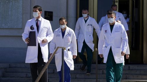 Dr. Sean Conley, physician to President Donald Trump, left, walks to brief reporters at Walter Reed National Military Medical Center in Bethesda, Md., Saturday, Oct. 3, 2020