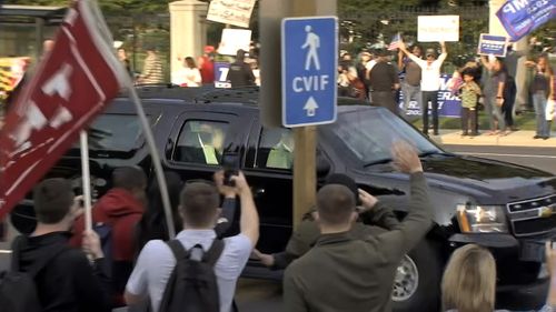 President Donald Trump waves as he drives past supporters gathered outside Walter Reed National Military Medical Center