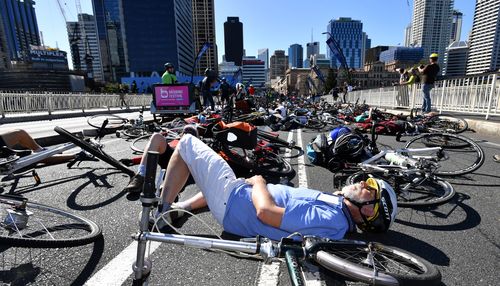 About 100 cyclists lay across two car lanes on Victoria Bridge in Brisbane this morning. (AAP)