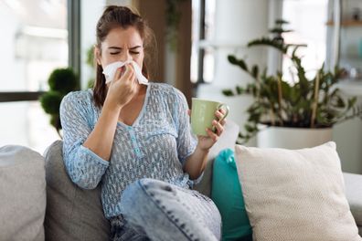 Young woman blowing her nose with a tissue at home