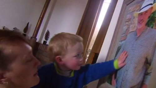 Baby Logan touches a photograph of his late father, Frank Lawlor. (9NEWS)