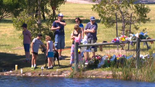 The Trott family visited the lake where Sam was found, taking time to read messages left for them. (9NEWS)