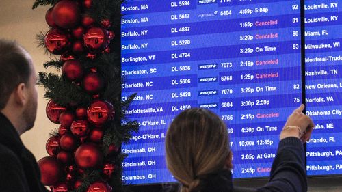 Passengers check flight departure schedule, some showing cancellations, as they arrive at the Delta terminal at Laguardia Airport, Friday Dec. 23, 2022, in New York. (AP Photo/Bebeto Matthews)