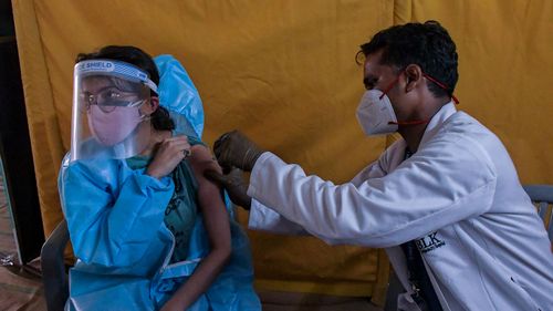 A young woman gets a coronavirus vaccine in New Delhi, India.