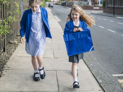 Two little girls excited for their first day back to school. Girls going to school. Kids going to school.