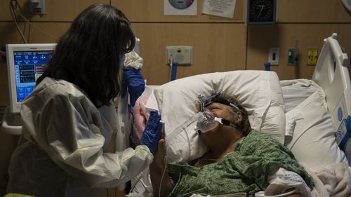 Becky Gonzalez, left, and her long time friend, Mary Lou Samora, a 71-year-old COVID-19 patient, put their palms together after they shared some encouraging words at Providence Holy Cross Medical Center in Los Angeles.