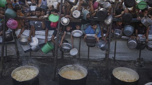 Palestinians struggle to get donated food at a community kitchen in Gaza City, northern Gaza Strip, Monday, July 14, 2025. (AP Photo/Jehad Alshrafi)