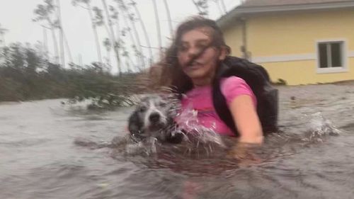 Julia Aylen wades through waist deep water carrying her pet dog as she is rescued from her flooded home during Hurricane Dorian in Freeport, Bahamas.