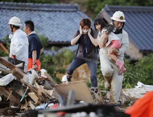 An emergency services worker rescues a young girl from amongst the rubble in Uwajima. Picture: AP
