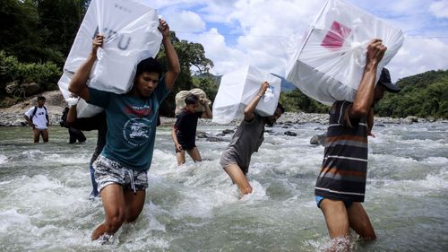 Indonesian election workers carry ballot boxes as they cross a river to deliver them to remote villages in Maros, South Sulawesi, Indonesia.