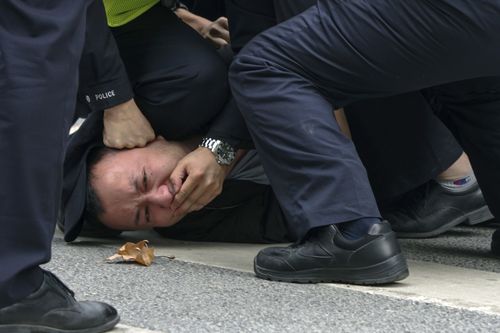 Chinese policemen pin down a protester and covered his mouth during a protest on a street in Shanghai, China on Nov. 27, 2022.