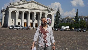 An injured man walks in Krasna square with the Taras Shevchenko Chernihiv Regional Academic Music and Drama Theatre in the background, after a Russian attack, in Chernihiv, Ukraine.