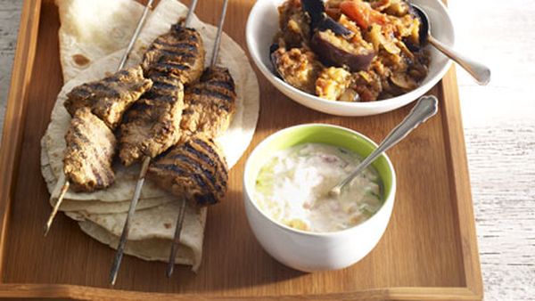 Lamb tikka kebabs with spiced eggplant, tomato raita and cucumber salad