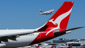 Qantas aircraft on tarmac and Jetstar plane flying in the background