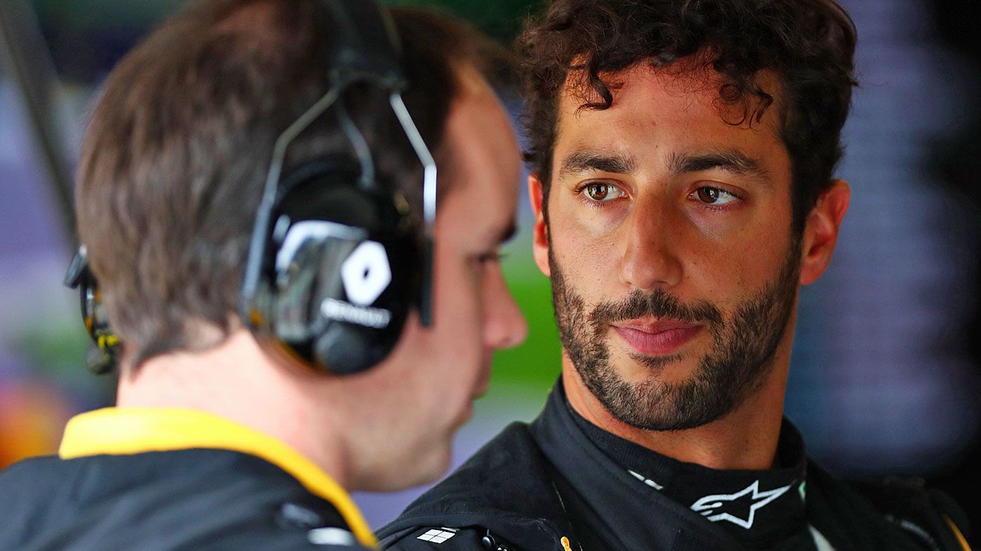 Daniel Ricciardo talks with a Renault Sport F1 team member in the garage 