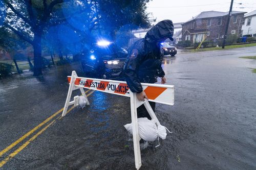 Policjant Charleston przesuwa barykadę, aby zablokować zalaną ulicę, na której odczuwalne są skutki huraganu Ian, piątek, 30 września 2022 r., Charleston w Południowej Karolinie 