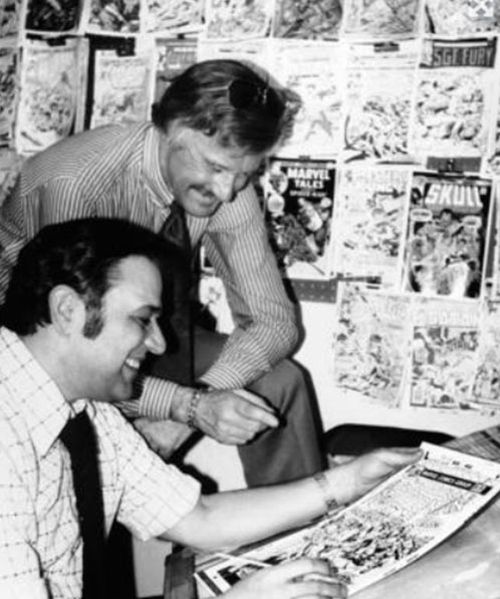 A file photo from 1976 showing Stan Lee, standing, publisher of Marvel Comics, discussing a "Spiderman" comic book cover with artist John Romita at Marvel headquarters in New York.
