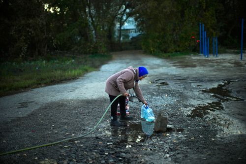 A woman refills plastic bottles with water in a well in Kivsharivka