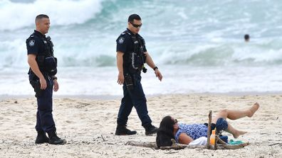 Queensland Police are seen moving on a sunbather from the beach at Burleigh Heads on April 10.  