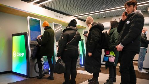 People stand in line to withdraw money from an ATM in Sberbank in St. Petersburg, Russia.