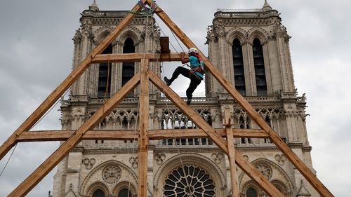 one of the carpenters puts the skills of their medieval colleagues on show on the plaza in front of Notre Dame Cathedral in Paris, France, Saturday, Sept. 19, 2020.