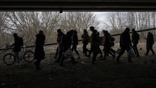 People cross on an improvised path under a bridge that was destroyed by a Russian airstrike, while fleeing the town of Irpin, Ukraine, Saturday, March 5, 2022. (AP Photo/Vadim Ghirda)