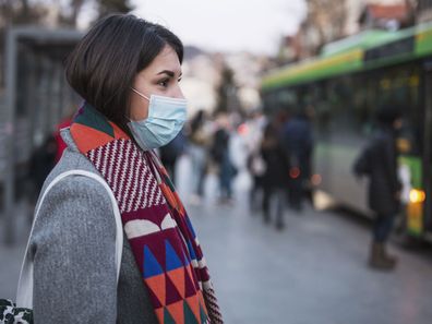 Woman in face masks waits for a bus