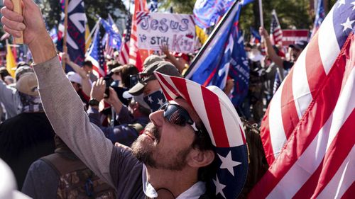 Rusty Albietz, of Blairsville, Ga., looks up at his flag while rallying with supporters of President Donald Trump outside of the Georgia State Capitol in Atlanta.