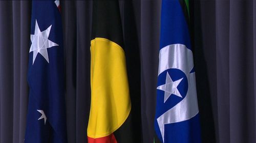 The Aboriginal and Torres Strait Islander flags hanging alongside the Australian flag during Anthony Albanese's first press conference as prime minister.