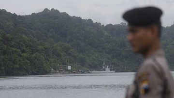 An Indonesian police stands guard as a ferry carrying Andrew Chan and Myuran Sukumaran arrives at Nusakambangan island. (AAP)