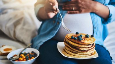 Cropped shot of a pregnant woman eating delicious pancakes at home