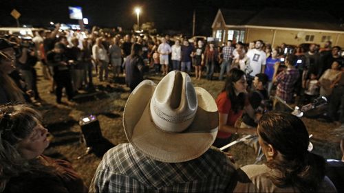 People attend a vigil near where a mass shooting took place at the First Baptist Church in Sutherland Springs. (Image: AAP)