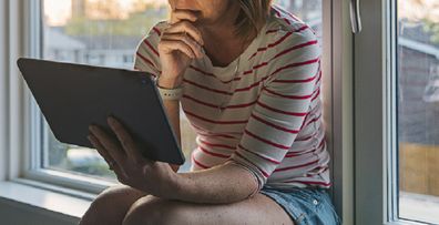 Woman sitting at home on computer sad