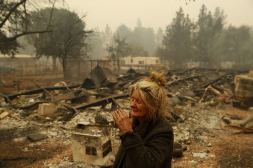 Cathy Fallon reacts as she stands near the charred remains of her home in Paradise, California.