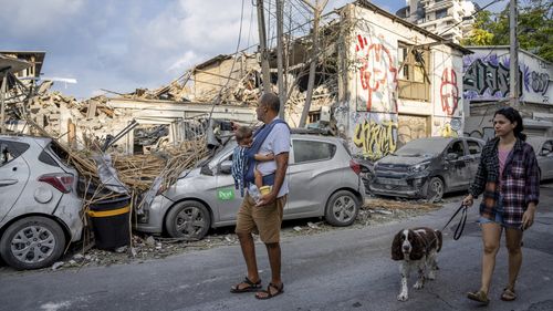 Israelis inspect the rubble of a building a day after it was hit by a rocket fired from the Gaza Strip, in Tel Aviv, Israel.
