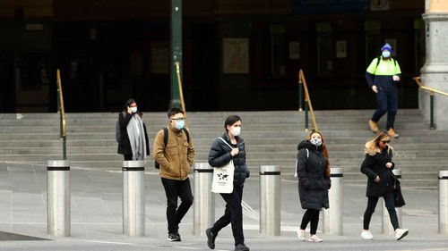 People are seen in front of Flinders Street Station.