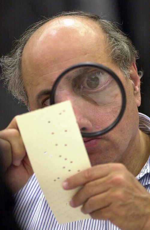 In another of Diaz's iconic photographs, canvassing board member Judge Robert Rosenberg uses a magnifying glass to examine a disputed election ballot. Picture: Alan Diaz / AP