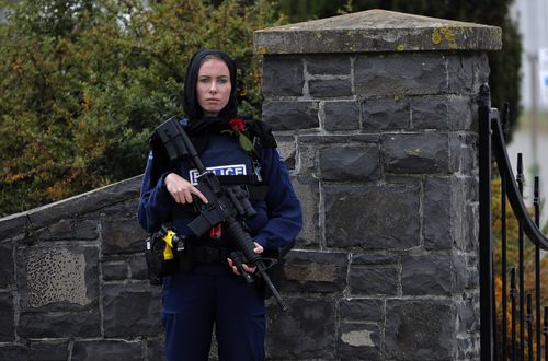 A police officer stands guard with a rose at the service for a victim of the attacks.