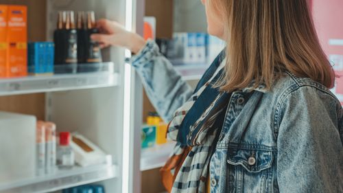 Woman chooses a cream at a pharmacy.