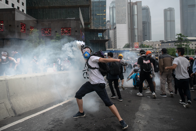 Protester throws back tear gas during a class with police.